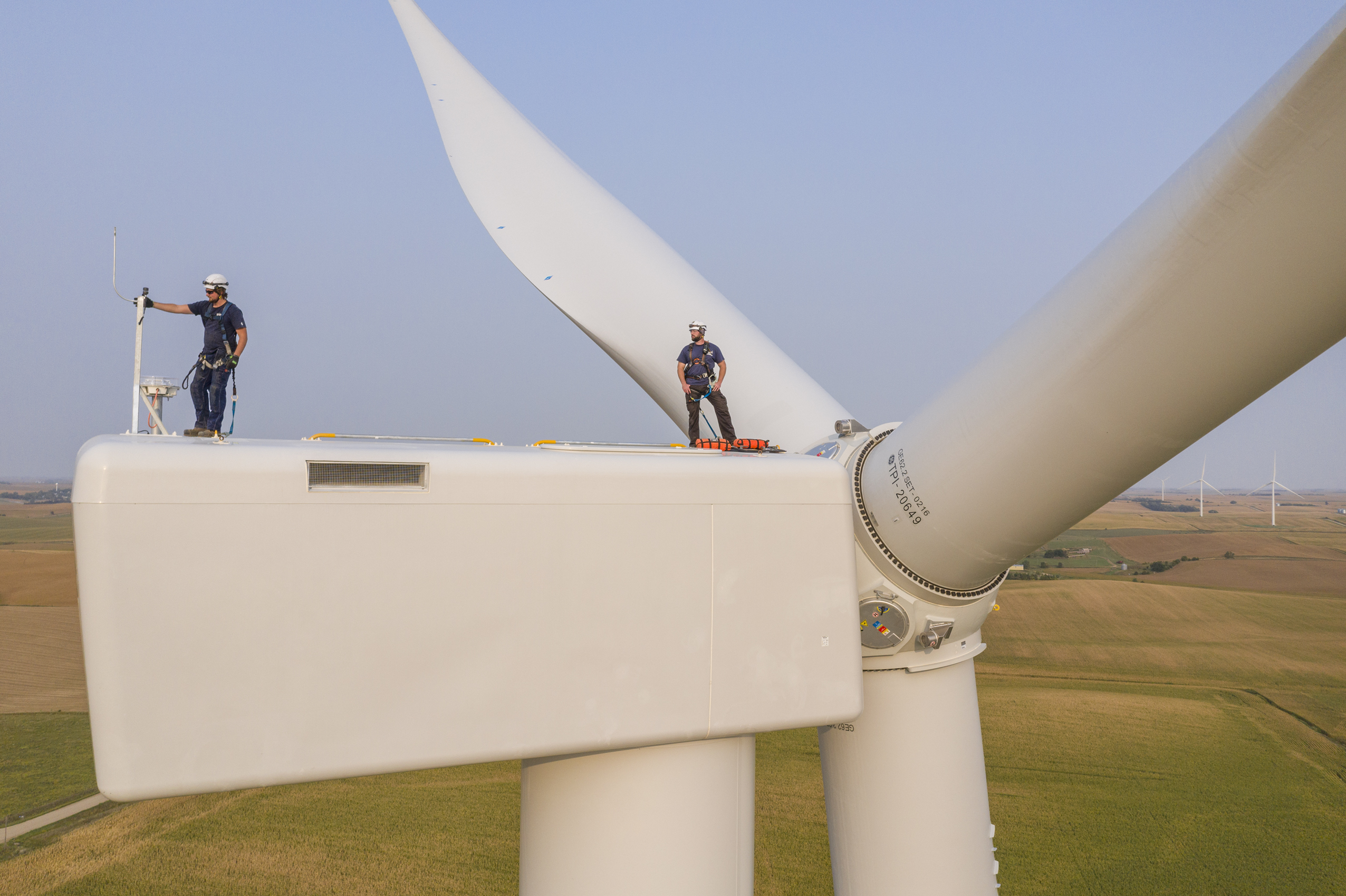 Drone view of two wind turbine techs on the top of the nacelle on Minnesota Wind Farm