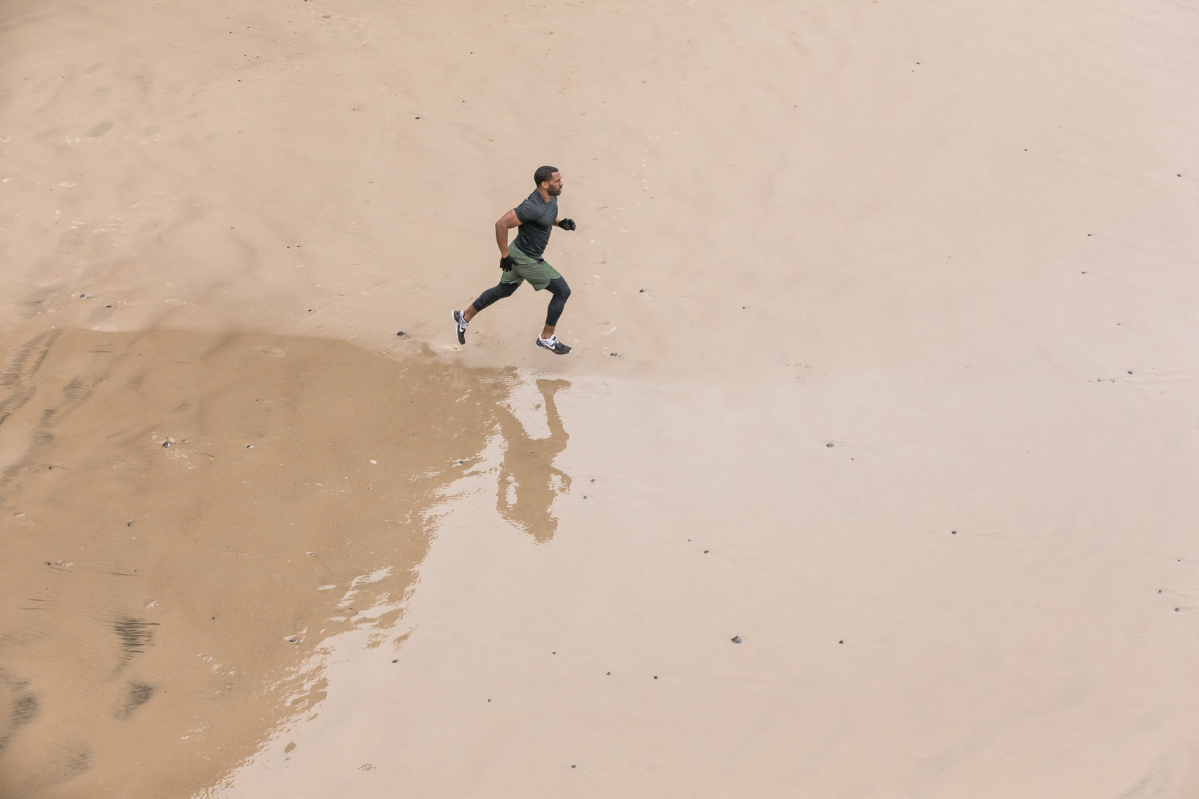 Athlete running on beach by fitness photographer Rich Crowder